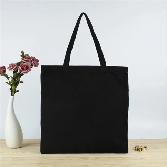Black Canvas Tote Bag next to a rose and white vase