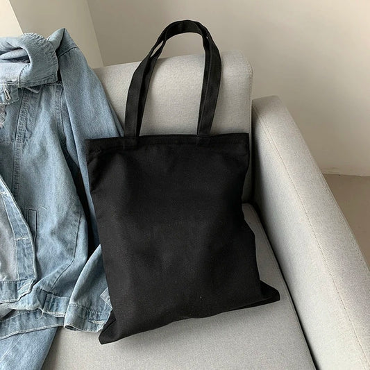 Black Tote Bag Canvas on a couch next to a jeans jacket
