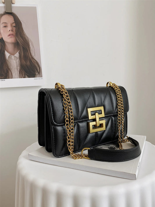 Chain Shoulder Bag in the color black on a white table next to a photo of a woman